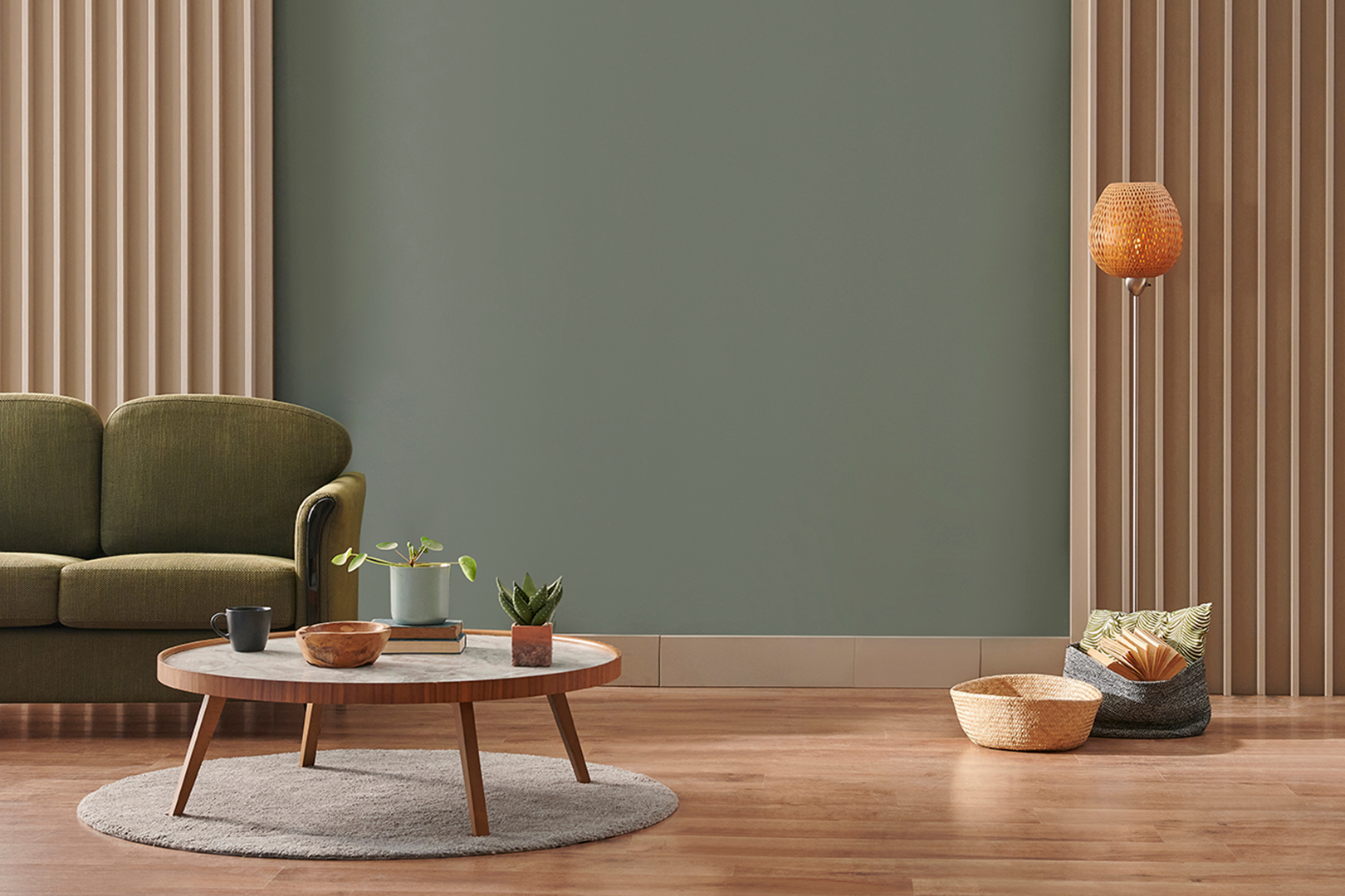 Wohnzimmer mit olivgrüner Wandfarbe, dunkelgrünem Sofa links und kleinem runden Sofatisch mit Pflanzen darauf.