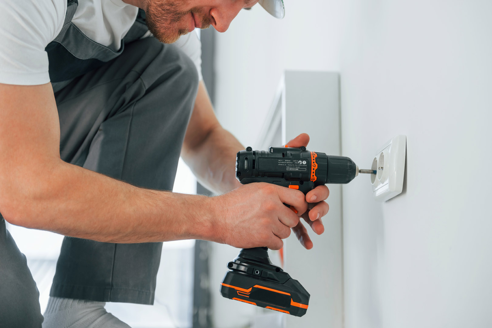 Nahaufnahme eines Handwerkers, der in einem Raum eine Steckdose anbringt
